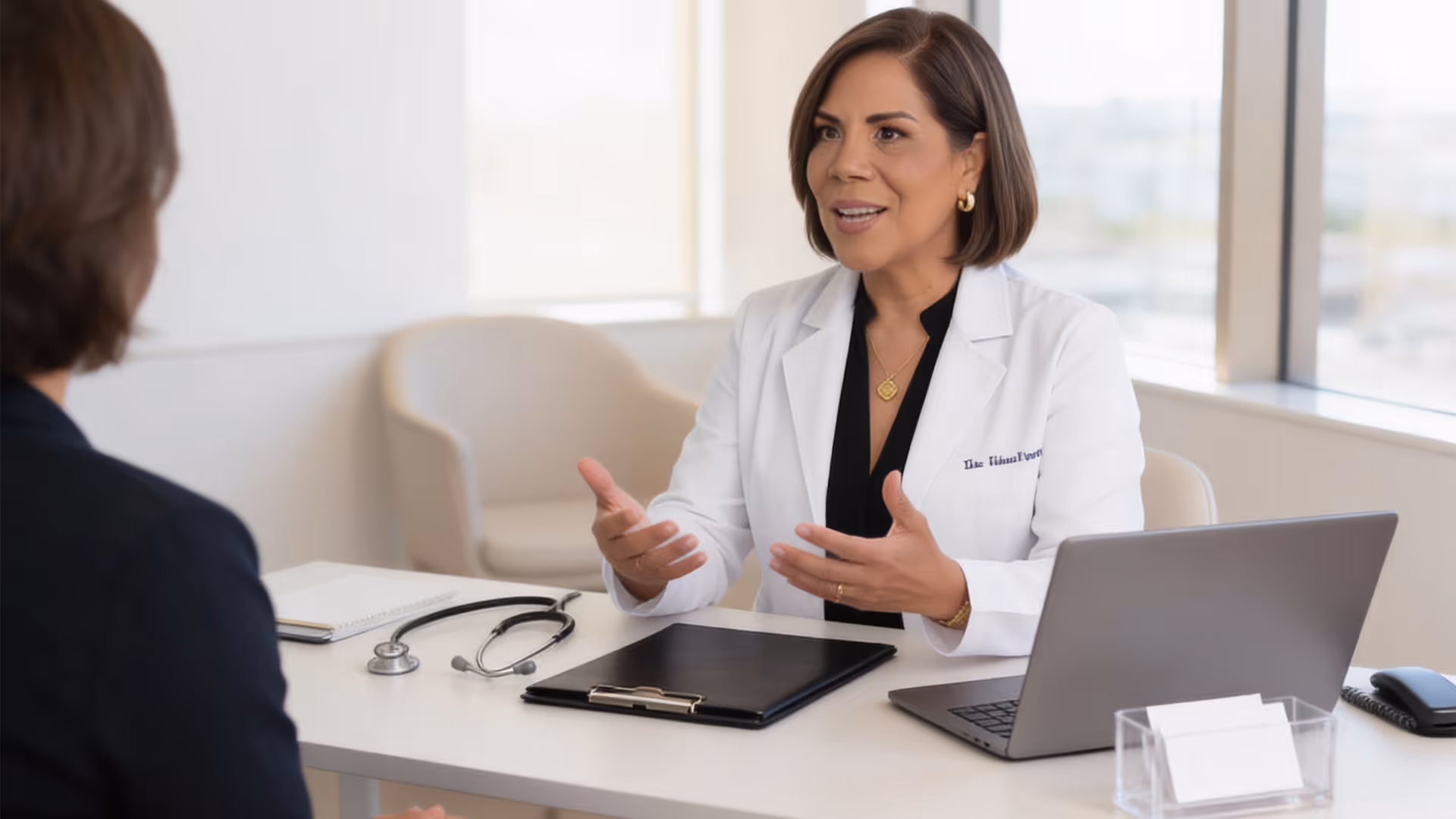 Doctora en bata blanca conversa con paciente en consulta médica moderna y luminosa.
